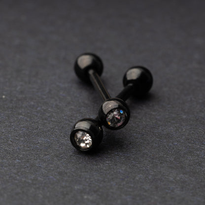 A set of black stainless steel nipple bars with polished gem-studded ends, displayed on a dark background.