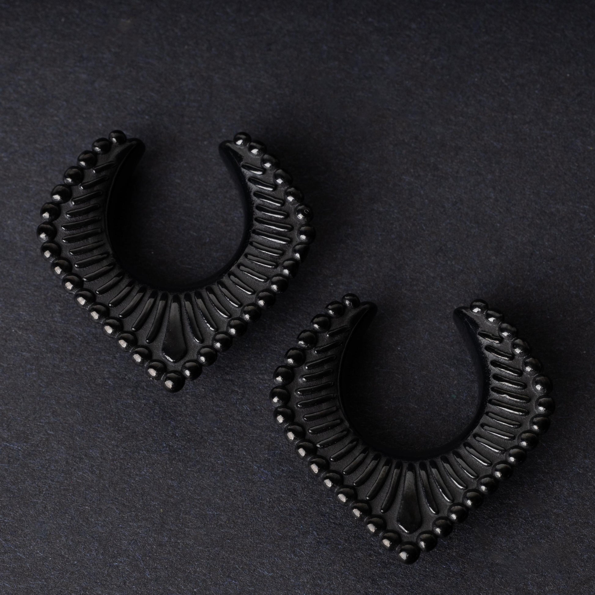 Black saddle hangers on a dark textured background.