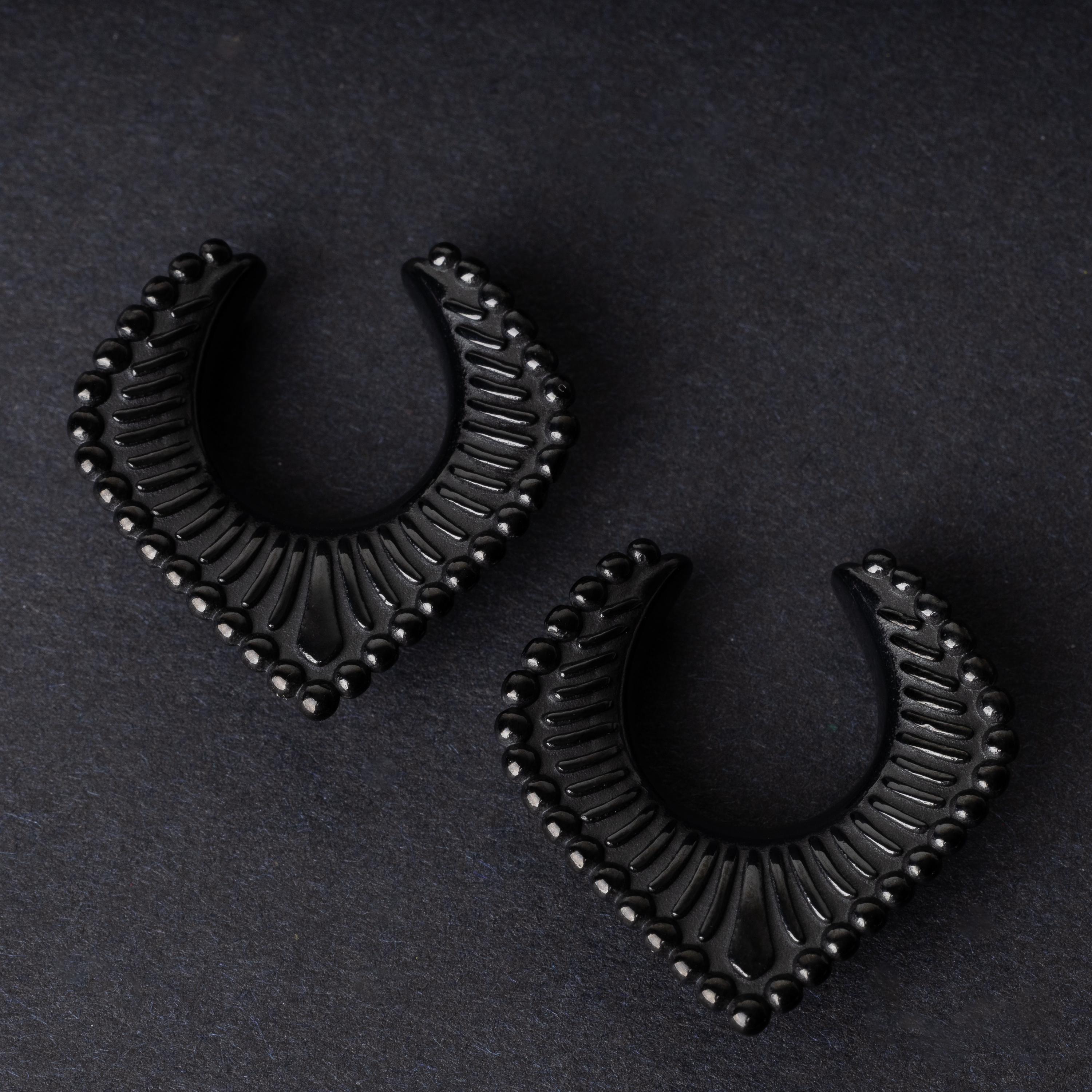 Black saddle hangers on a dark textured background.
