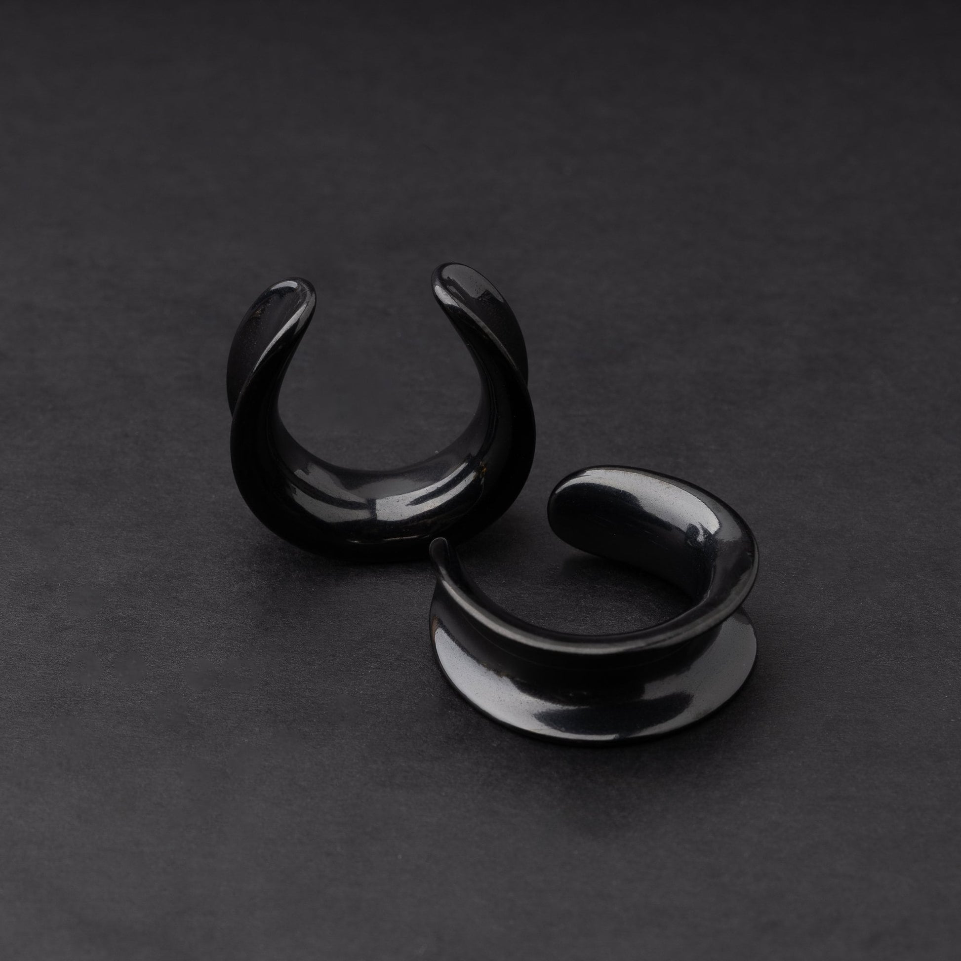 A pair of black saddle tunnels displayed on a dark background.