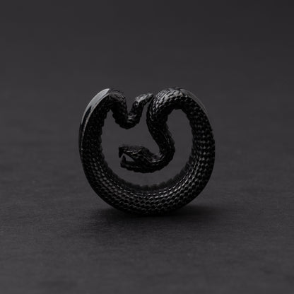 Black Snake-shaped saddle plugs, displayed on a dark background.