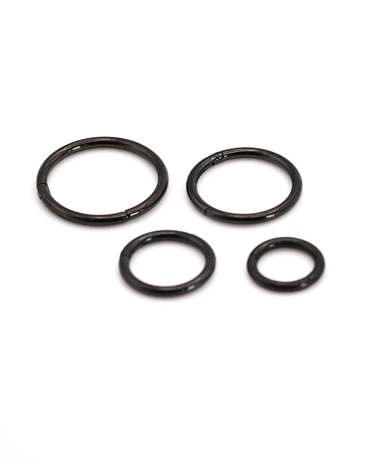 A selection of black coloured titanium clicker hoops on a white background. 

