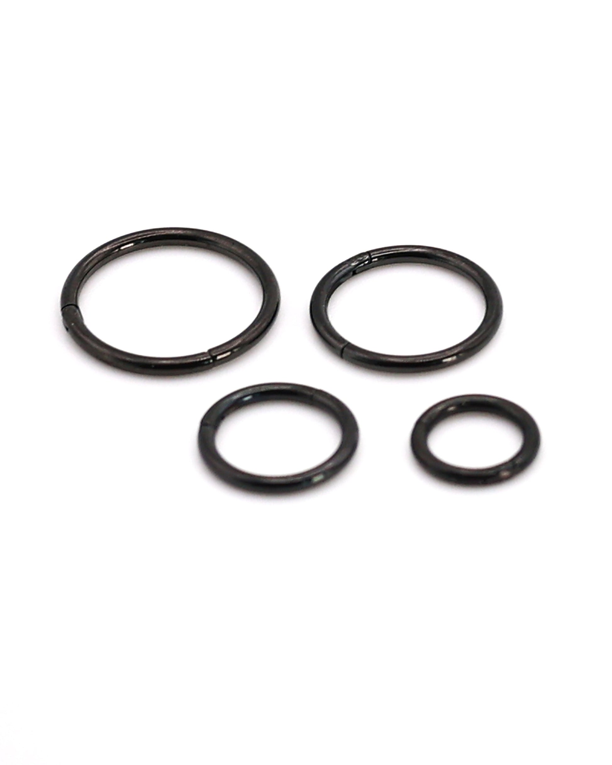 A selection of black coloured titanium clicker hoops on a white background. 

