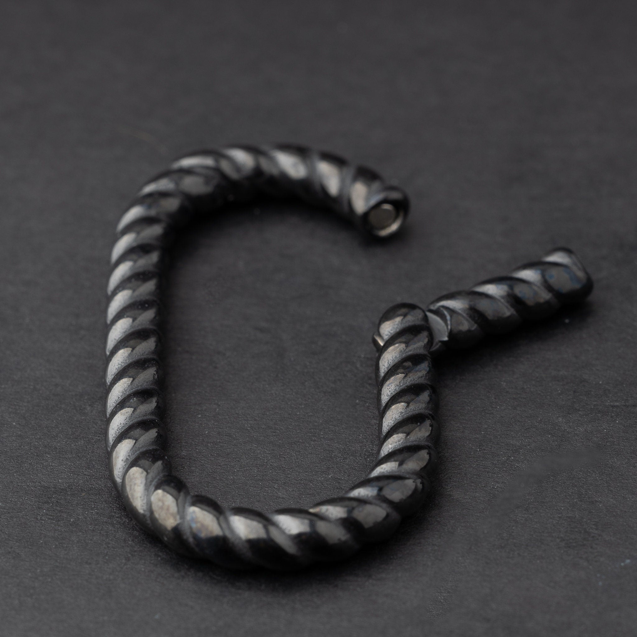 Twisted ear hangers in a black finish displayed on a dark background, showcasing their rope-like design and bold style.