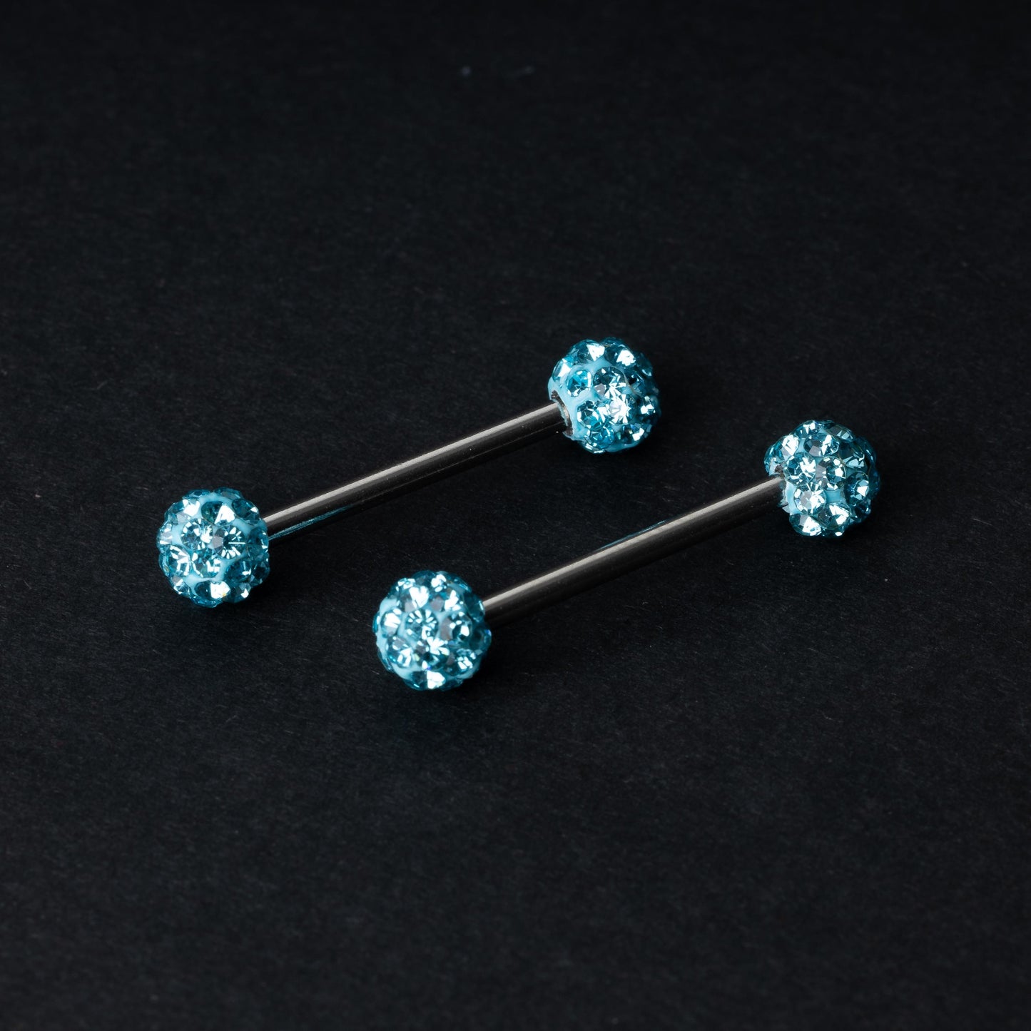 Barbells with textured crystal-encrusted ends in icy blue displayed on a dark background.