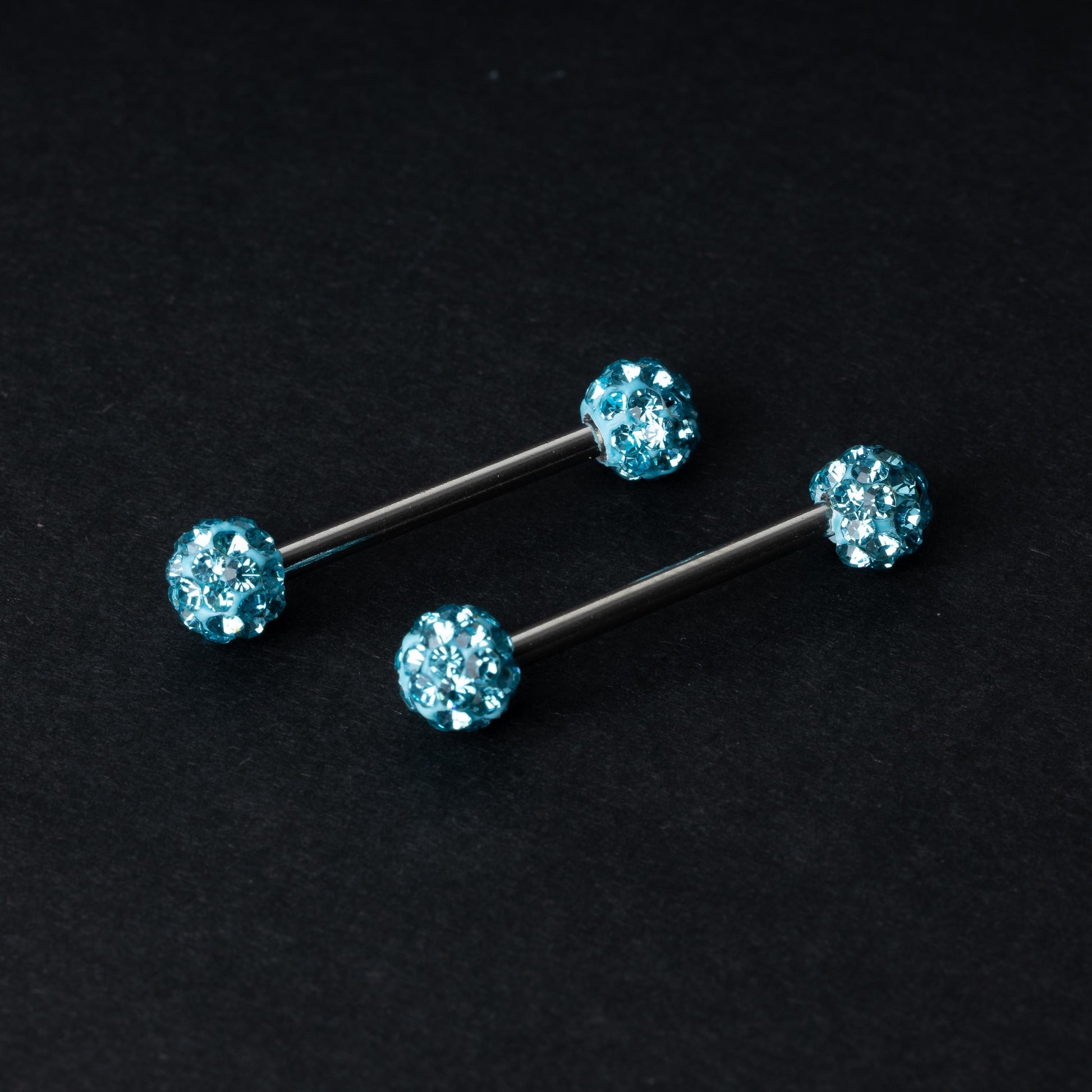 Barbells with textured crystal-encrusted ends in icy blue displayed on a dark background.