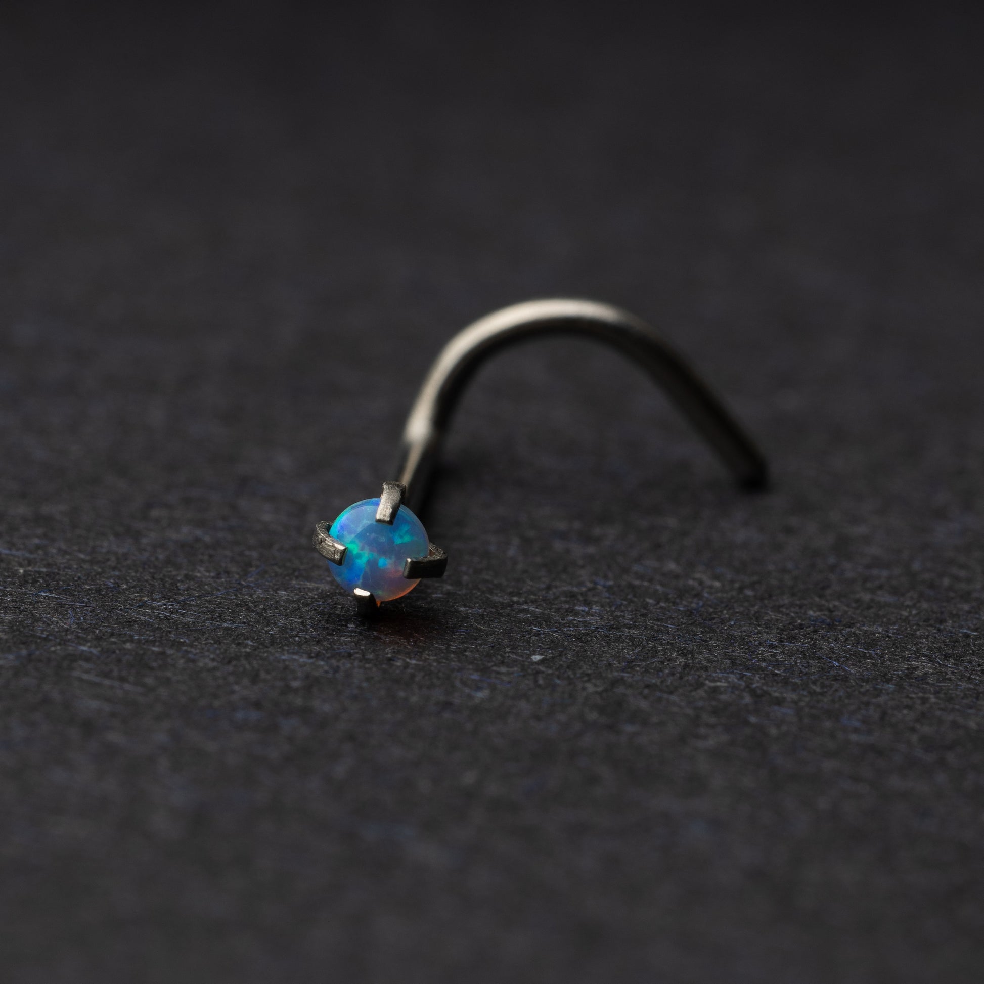 Single opalescent nose screw with a prong setting, displayed on a dark background.