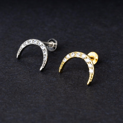 Close-up of gold and silver crescent moon stud earrings featuring CZ gems, displayed on a dark background.