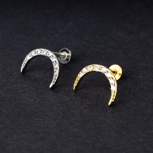 Close-up of gold and silver crescent moon stud earrings featuring CZ gems, displayed on a dark background.