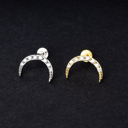 Close-up of gold and silver crescent moon stud earrings featuring CZ gems, displayed on a dark background.