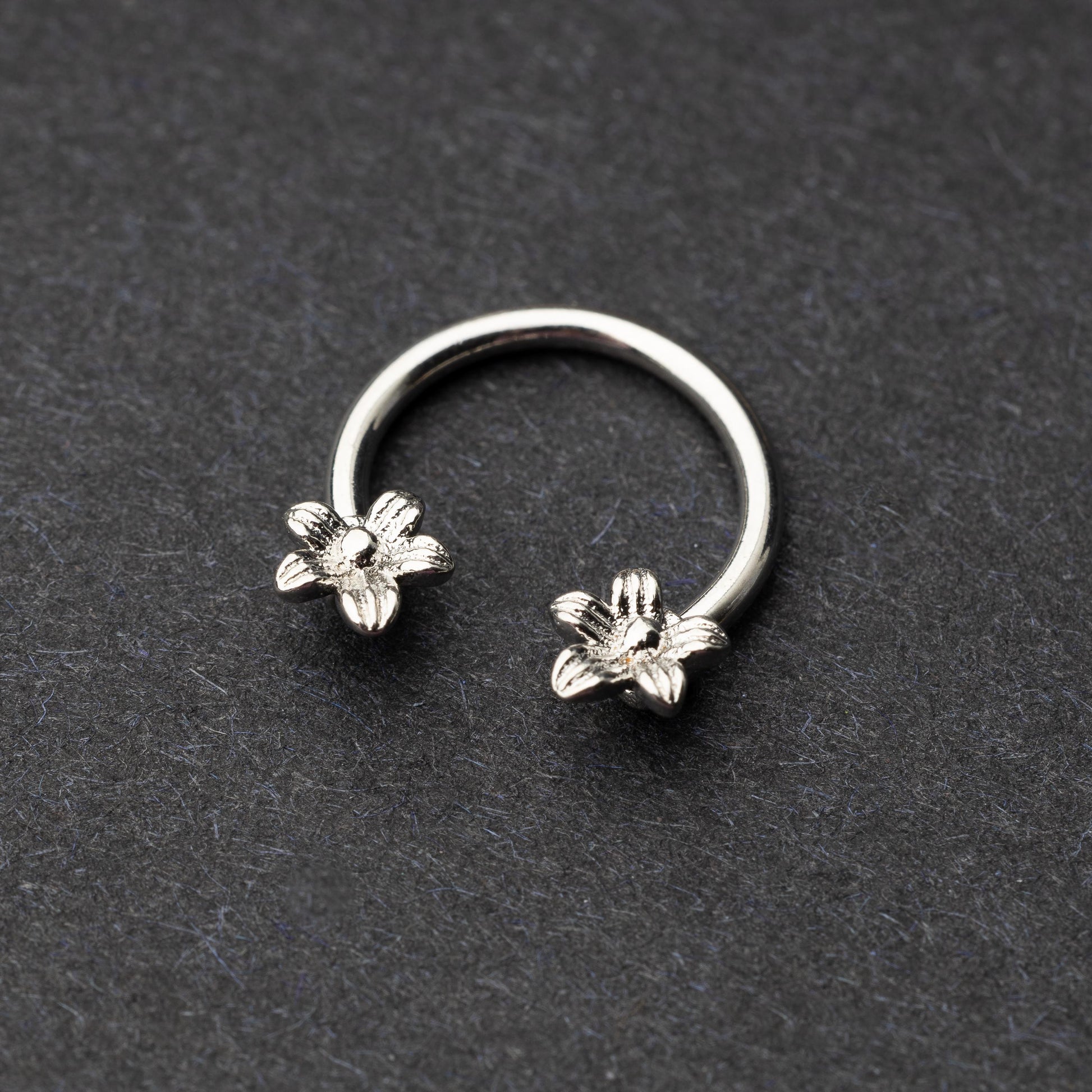 Horseshoe hoop featuring a flower charm, displayed on a dark background.