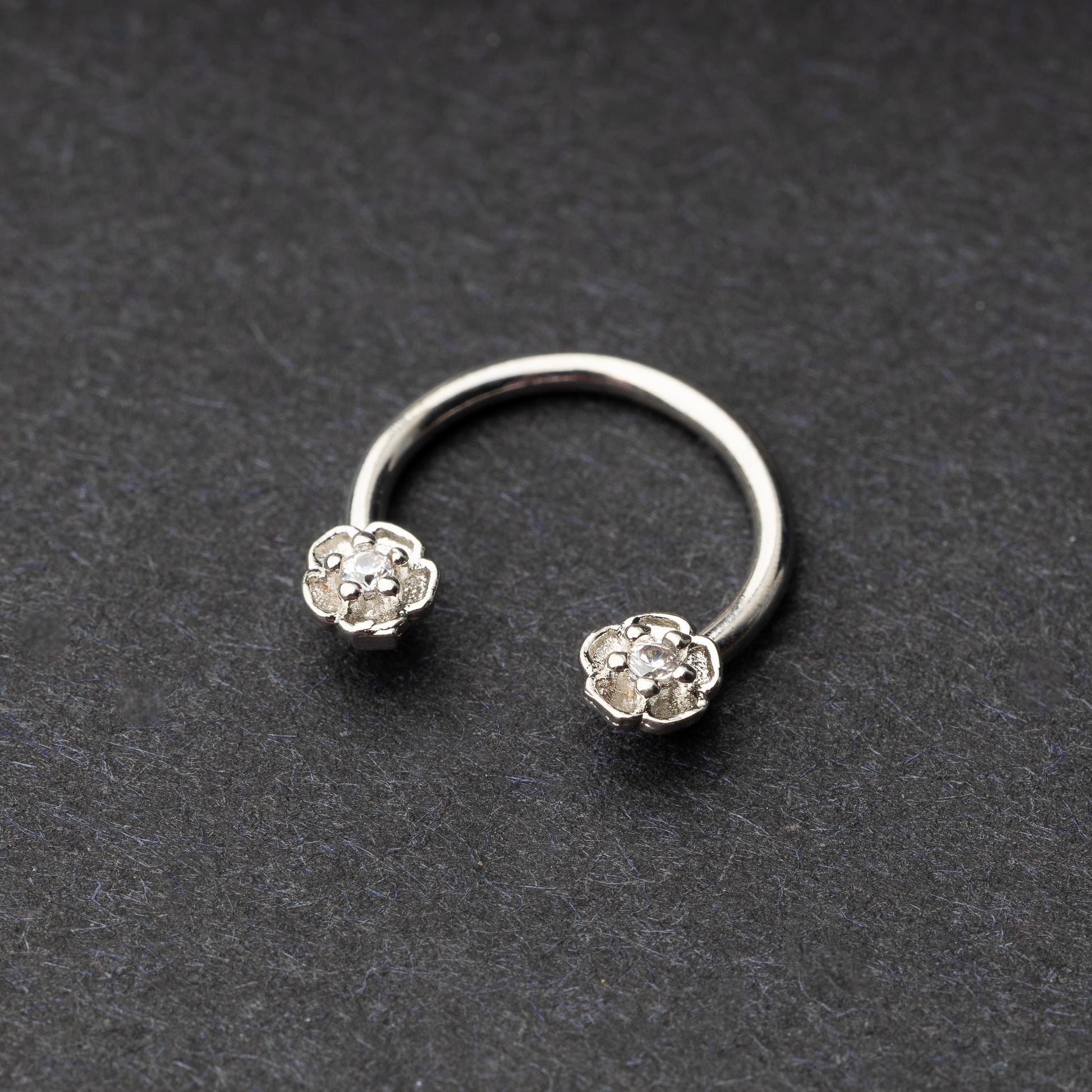 Horseshoe hoop featuring a flower charm, displayed on a dark background.