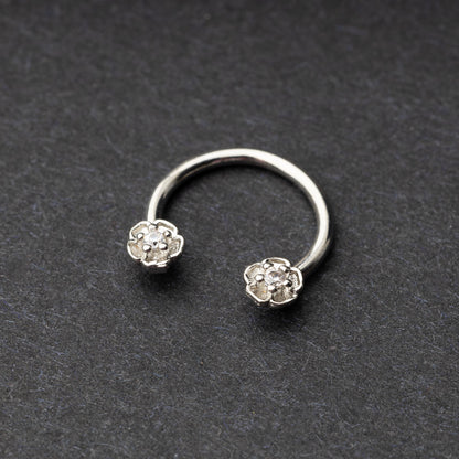 Horseshoe hoop featuring a flower charm, displayed on a dark background.
