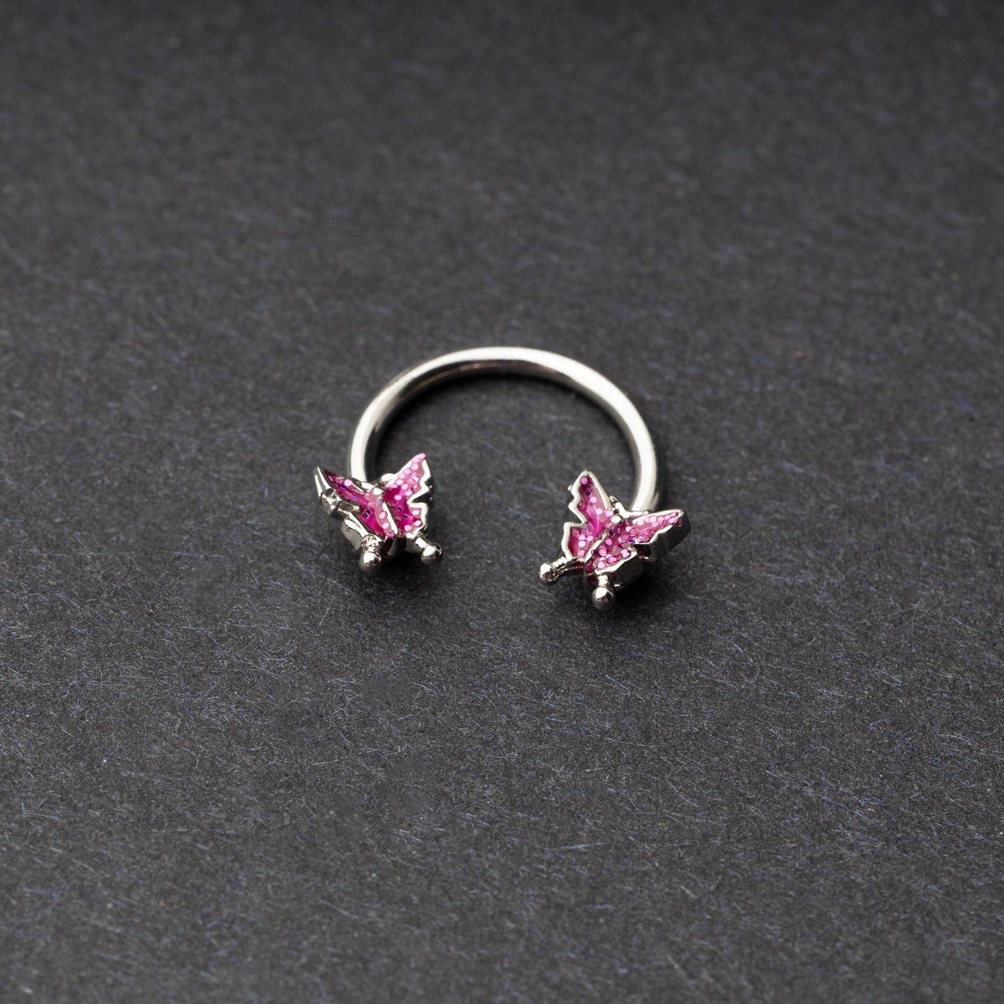 Horseshoe hoop featuring a butterfly charm, displayed on a dark background.