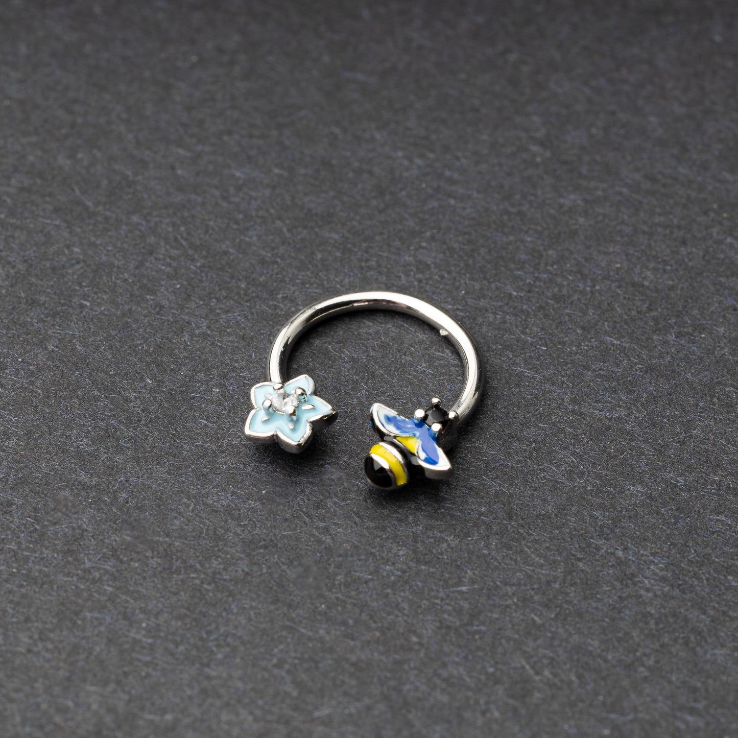 Horseshoe hoop featuring bee and flower charms, displayed on a dark background.