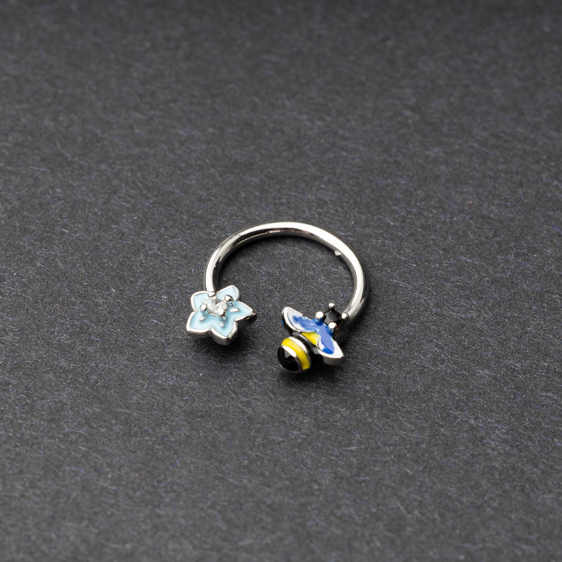 Horseshoe hoop featuring bee and flower charms, displayed on a dark background.