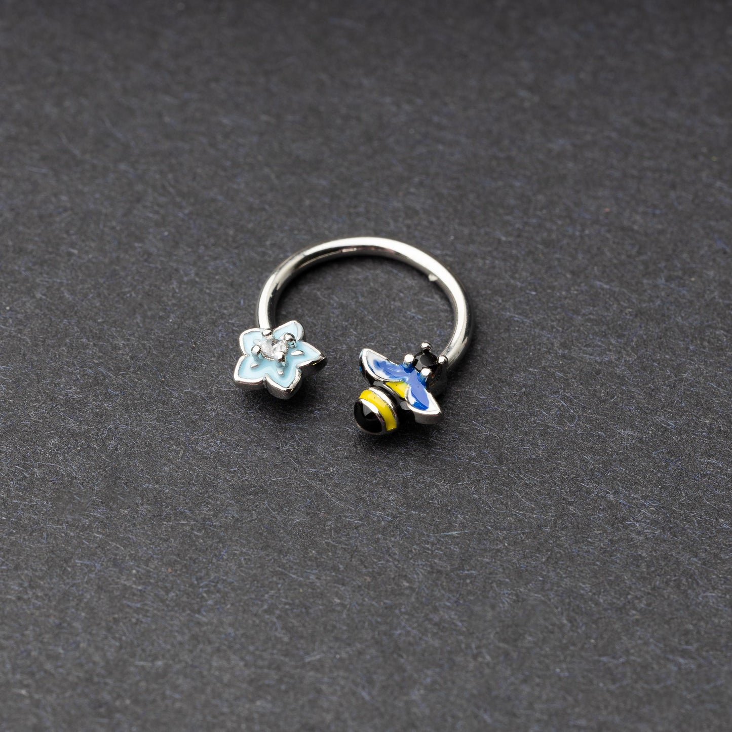 Horseshoe hoop featuring bee and flower charms, displayed on a dark background.
