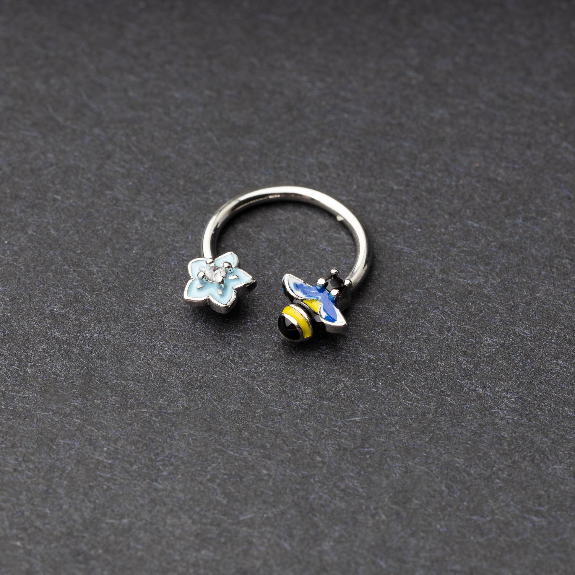 Horseshoe hoop featuring bee and flower charms, displayed on a dark background.