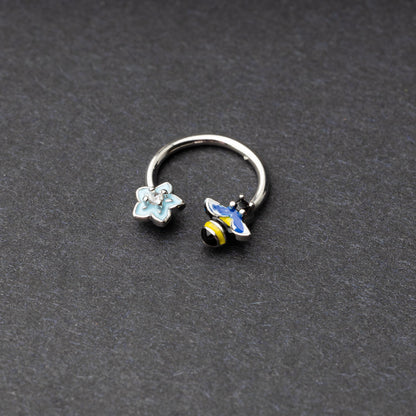 Horseshoe hoop featuring bee and flower charms, displayed on a dark background.