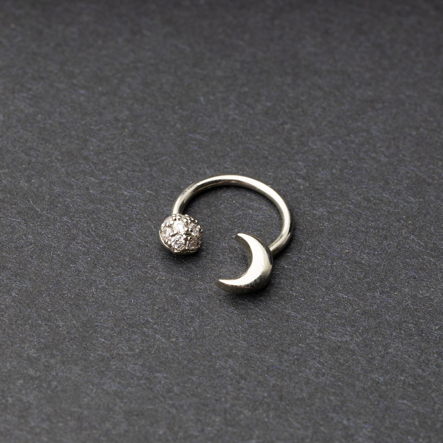 Horseshoe hoop featuring moon charms, displayed on a dark background.