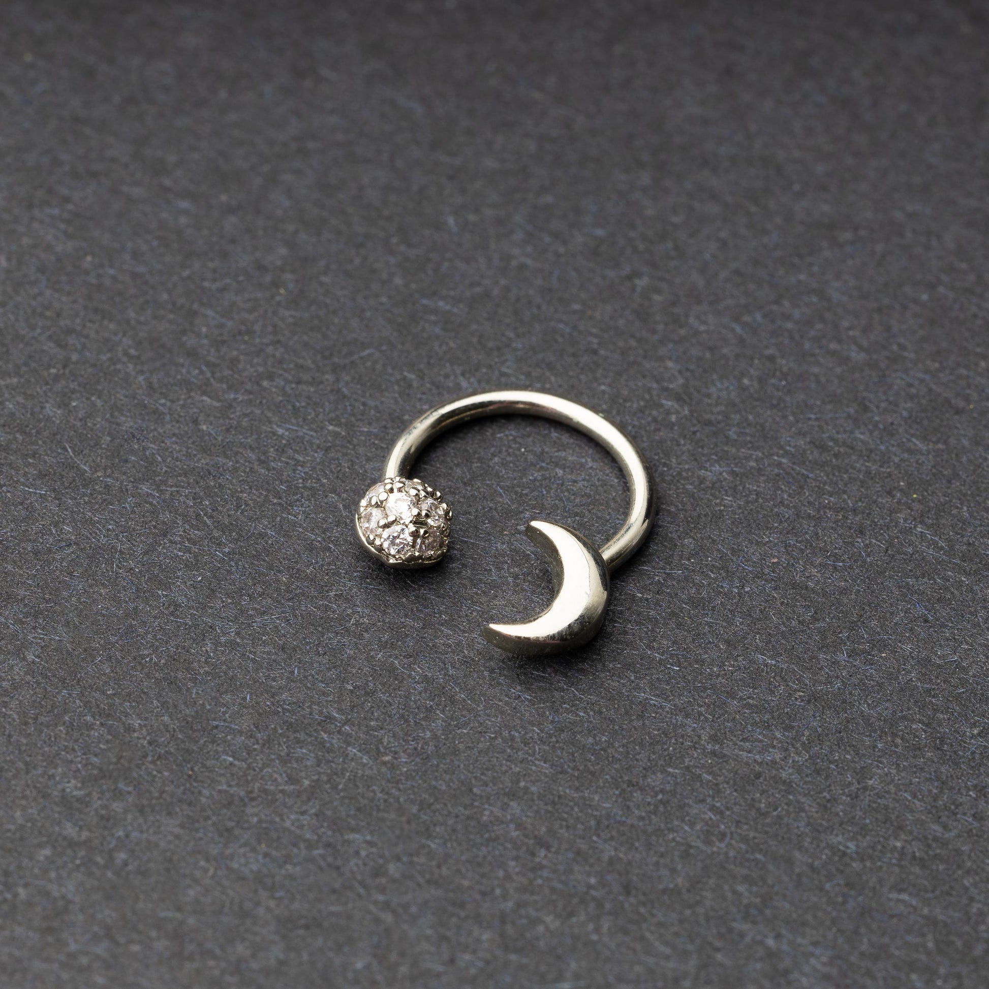 Horseshoe hoop featuring moon charms, displayed on a dark background.