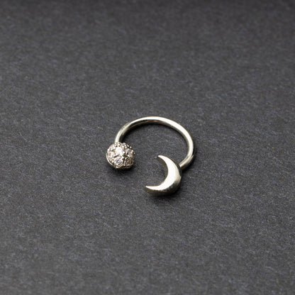 Horseshoe hoop featuring moon charms, displayed on a dark background.