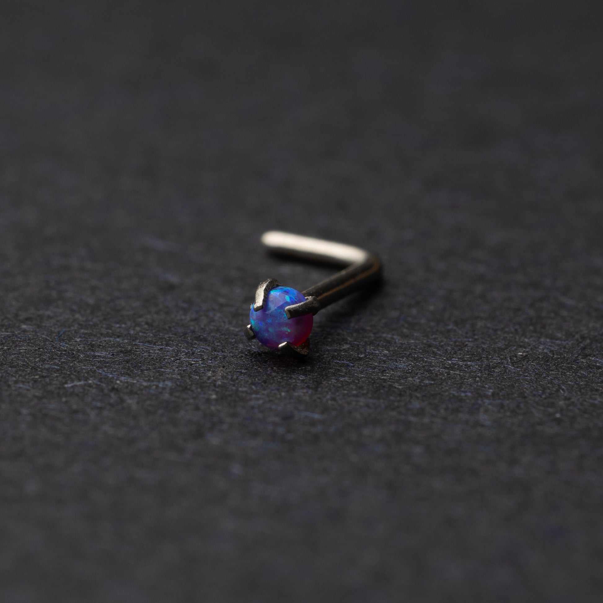 Opal L shaped nose stud on a dark background
