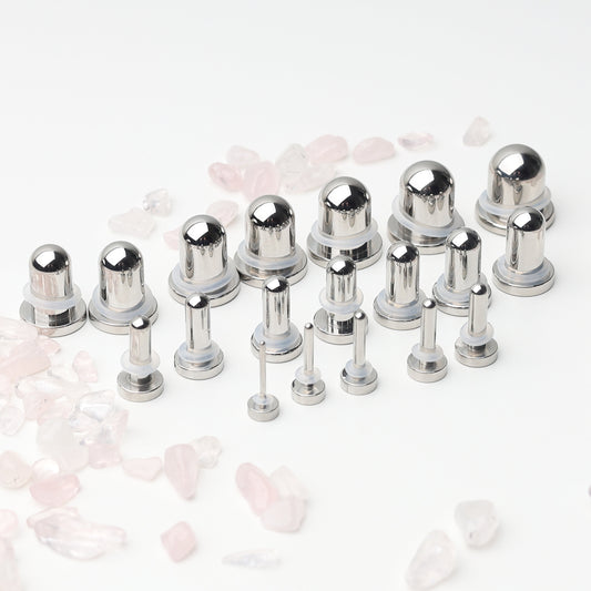 A complete dead stretching kit with polished stainless steel plugs and tunnels in multiple sizes, displayed on a white background with scattered rose quartz accents.