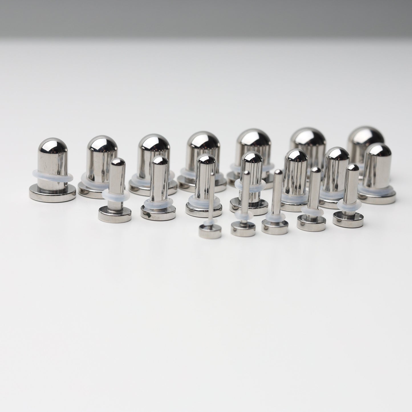 A complete dead stretching kit with polished stainless steel plugs and tunnels in multiple sizes, displayed on a white background