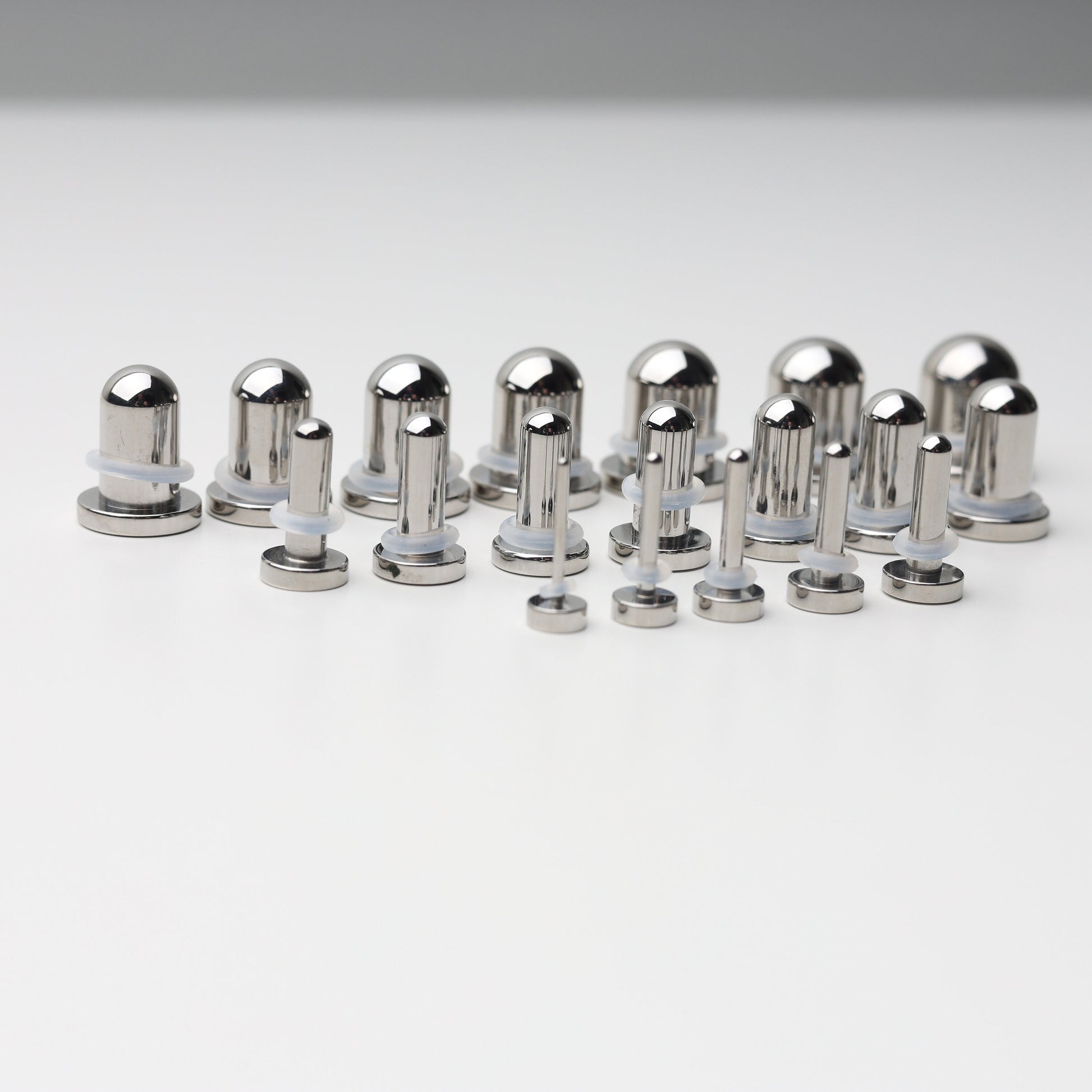 A complete dead stretching kit with polished stainless steel plugs and tunnels in multiple sizes, displayed on a white background