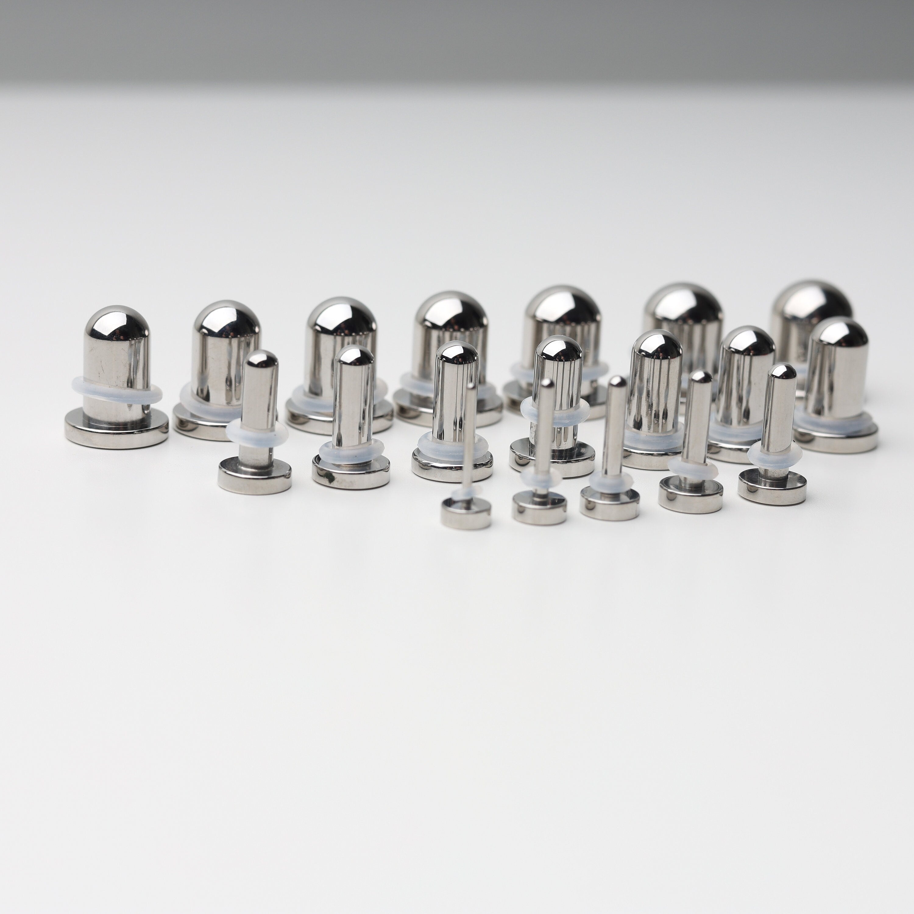 A complete dead stretching kit with polished stainless steel plugs and tunnels in multiple sizes, displayed on a white background