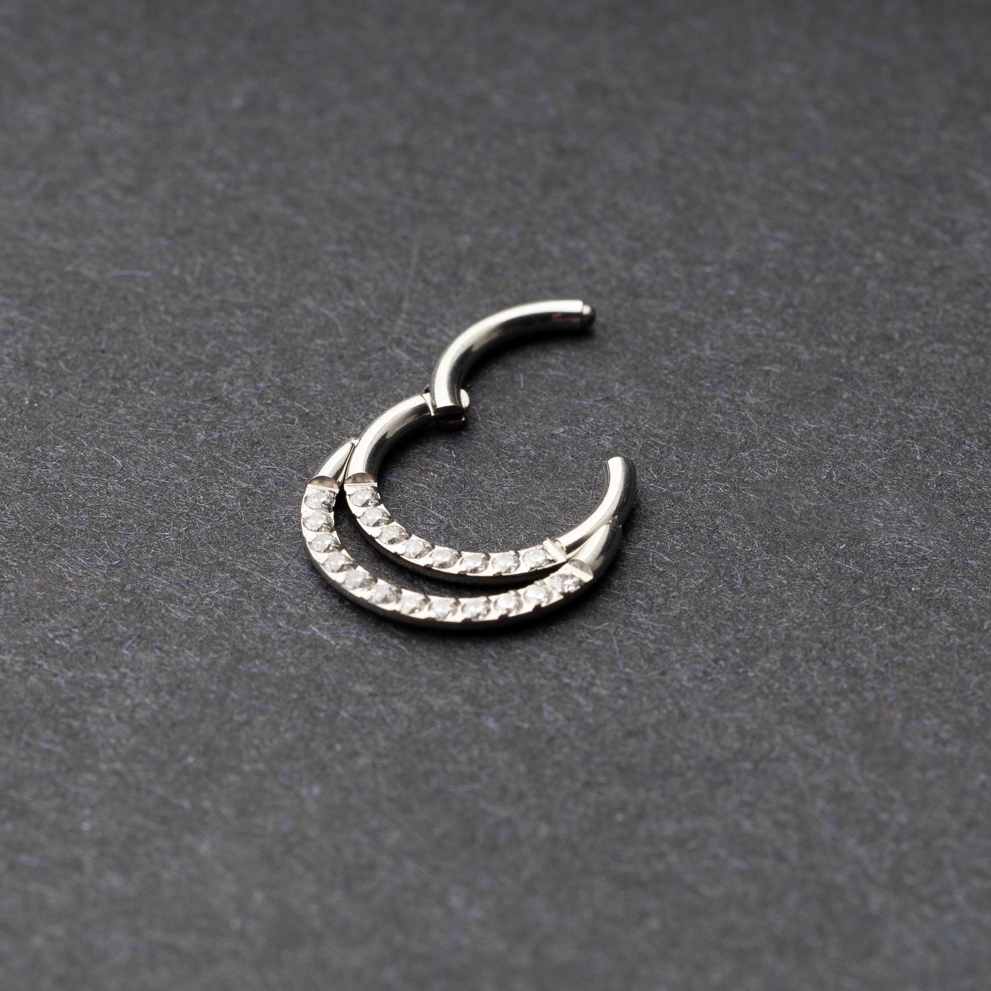 Titanium double-layered clicker with sparkling cubic zirconia accents, displayed on a dark background.