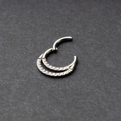 Titanium double-layered clicker with sparkling cubic zirconia accents, displayed on a dark background.