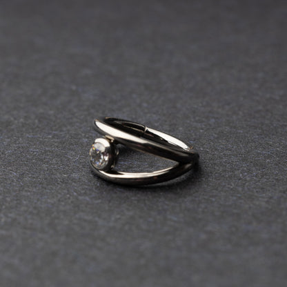 Titanium double-layered clicker with a single cubic zirconia centerpiece, displayed on a dark background.