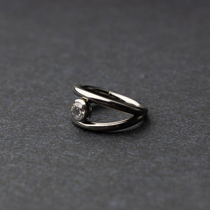 Titanium double-layered clicker with a single cubic zirconia centerpiece, displayed on a dark background.