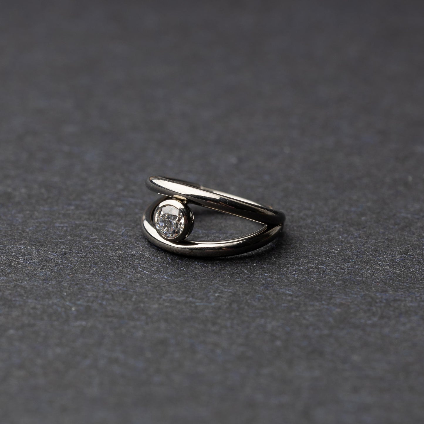 Titanium double-layered clicker with a single cubic zirconia centerpiece, displayed on a dark background.