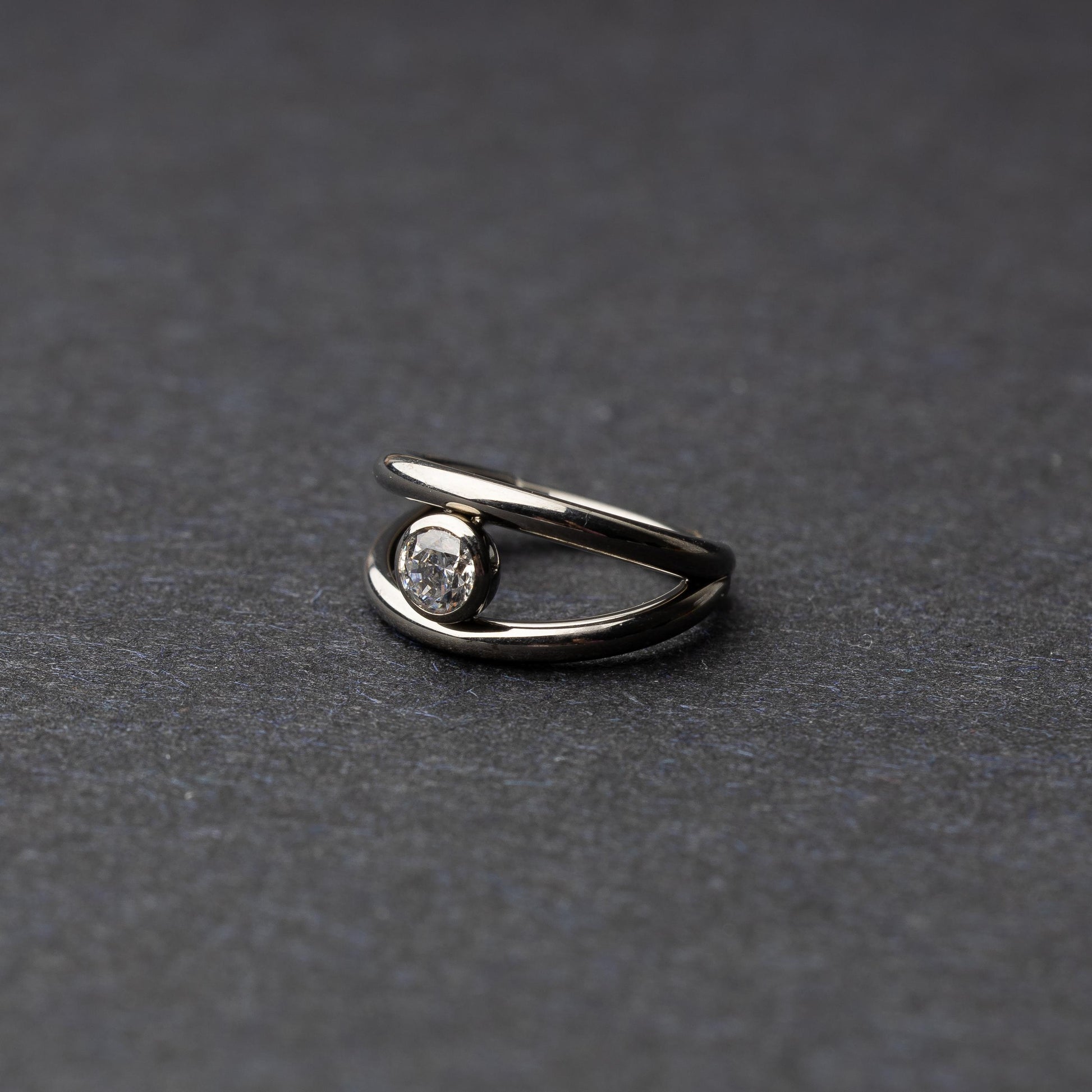 Titanium double-layered clicker with a single cubic zirconia centerpiece, displayed on a dark background.