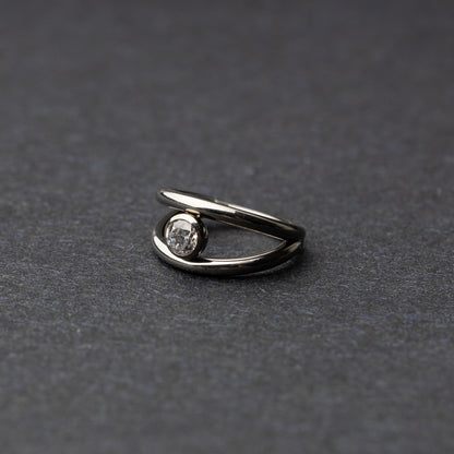 Titanium double-layered clicker with a single cubic zirconia centerpiece, displayed on a dark background.