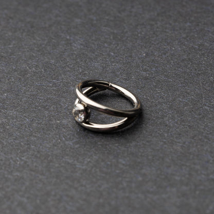 Titanium double-layered clicker with a single cubic zirconia centerpiece, displayed on a dark background.