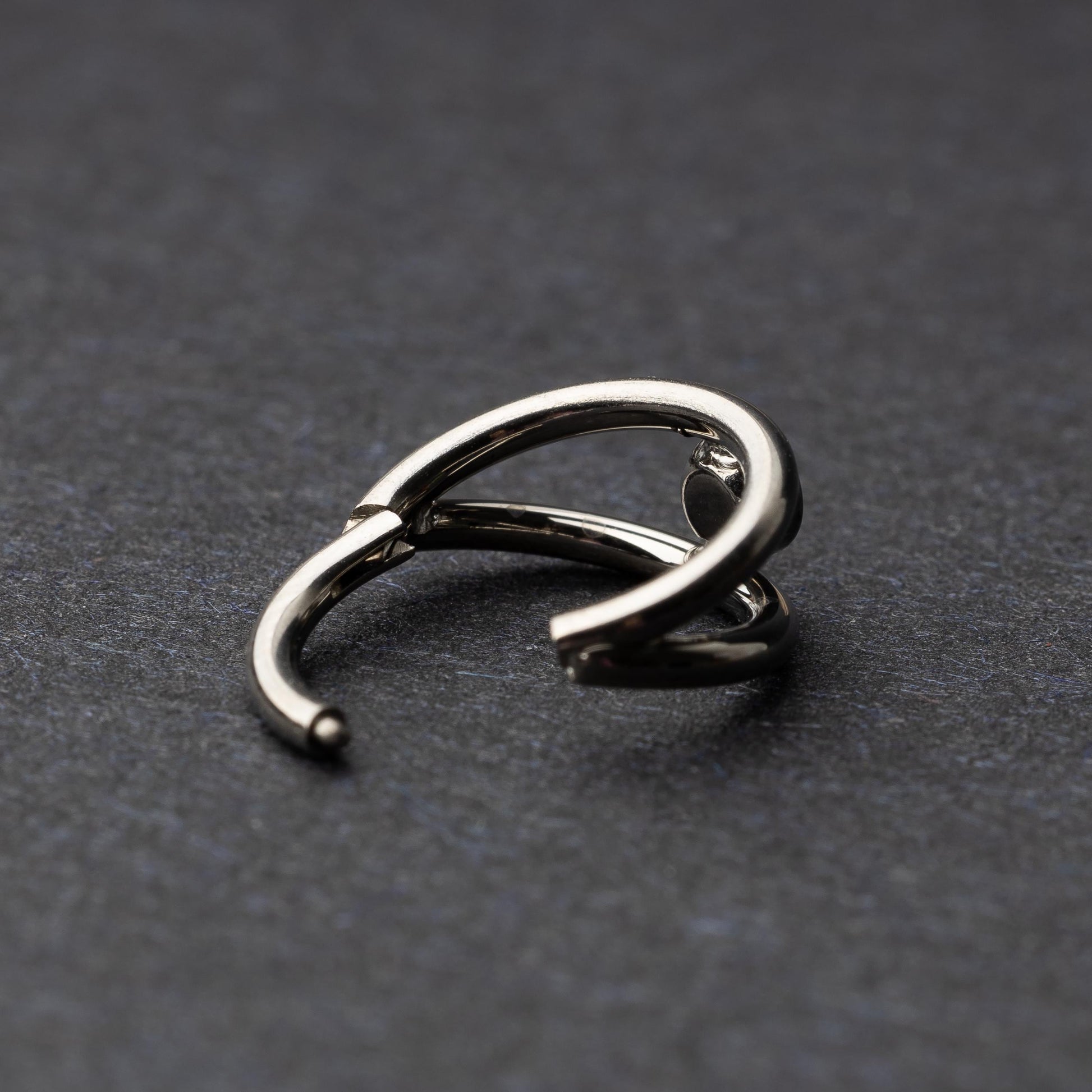 Titanium double-layered clicker with a single cubic zirconia centerpiece, displayed on a dark background.