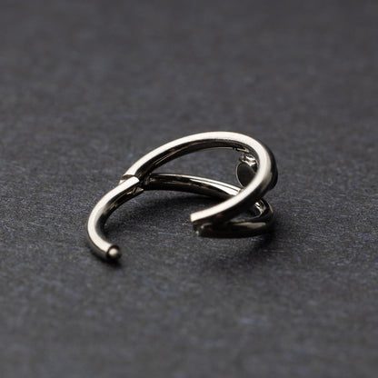 Titanium double-layered clicker with a single cubic zirconia centerpiece, displayed on a dark background.