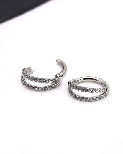 Titanium double-row clickers with cubic zirconia accents, displayed on a textured white background.