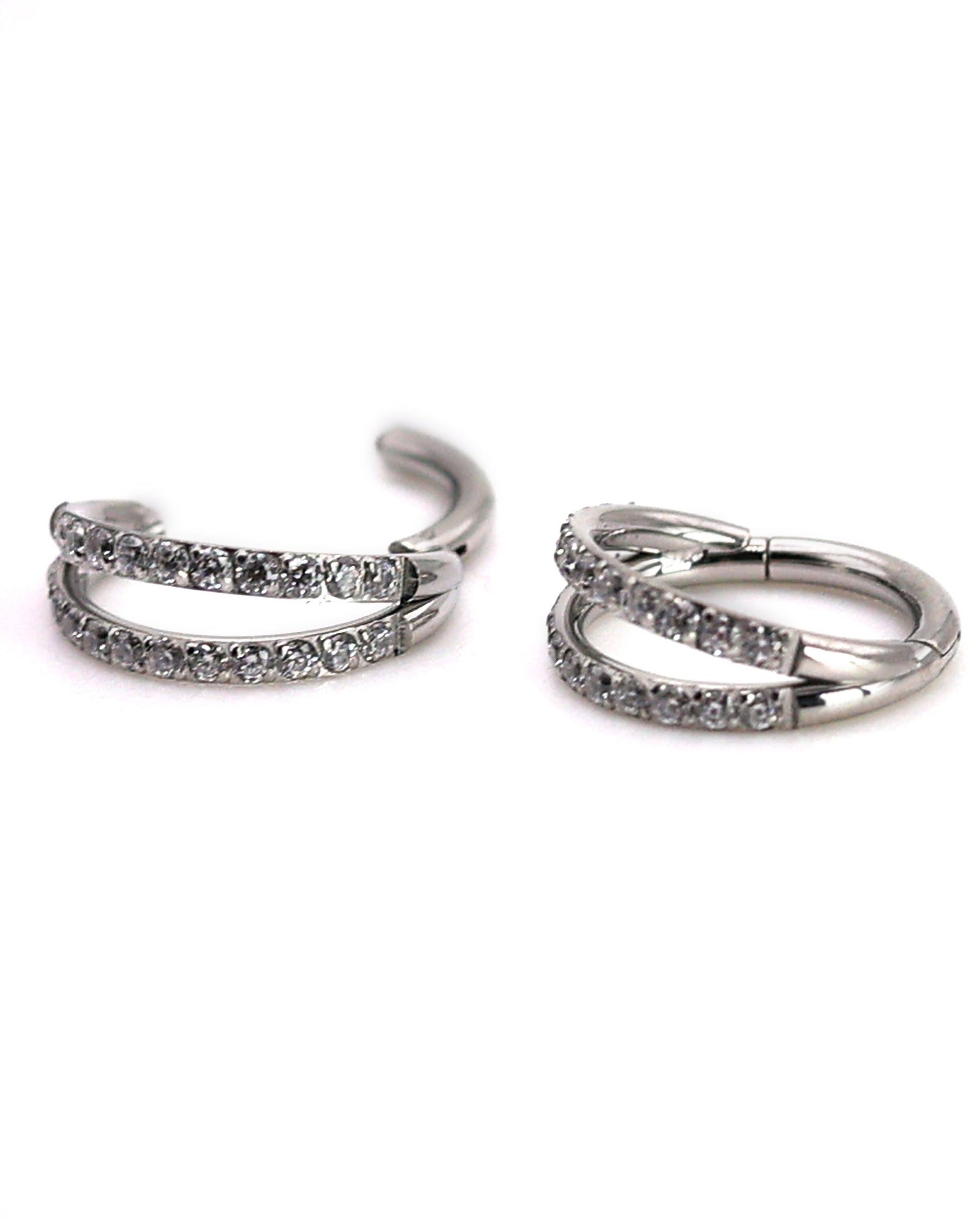 Titanium double-row clickers with cubic zirconia accents, displayed on a textured white background.