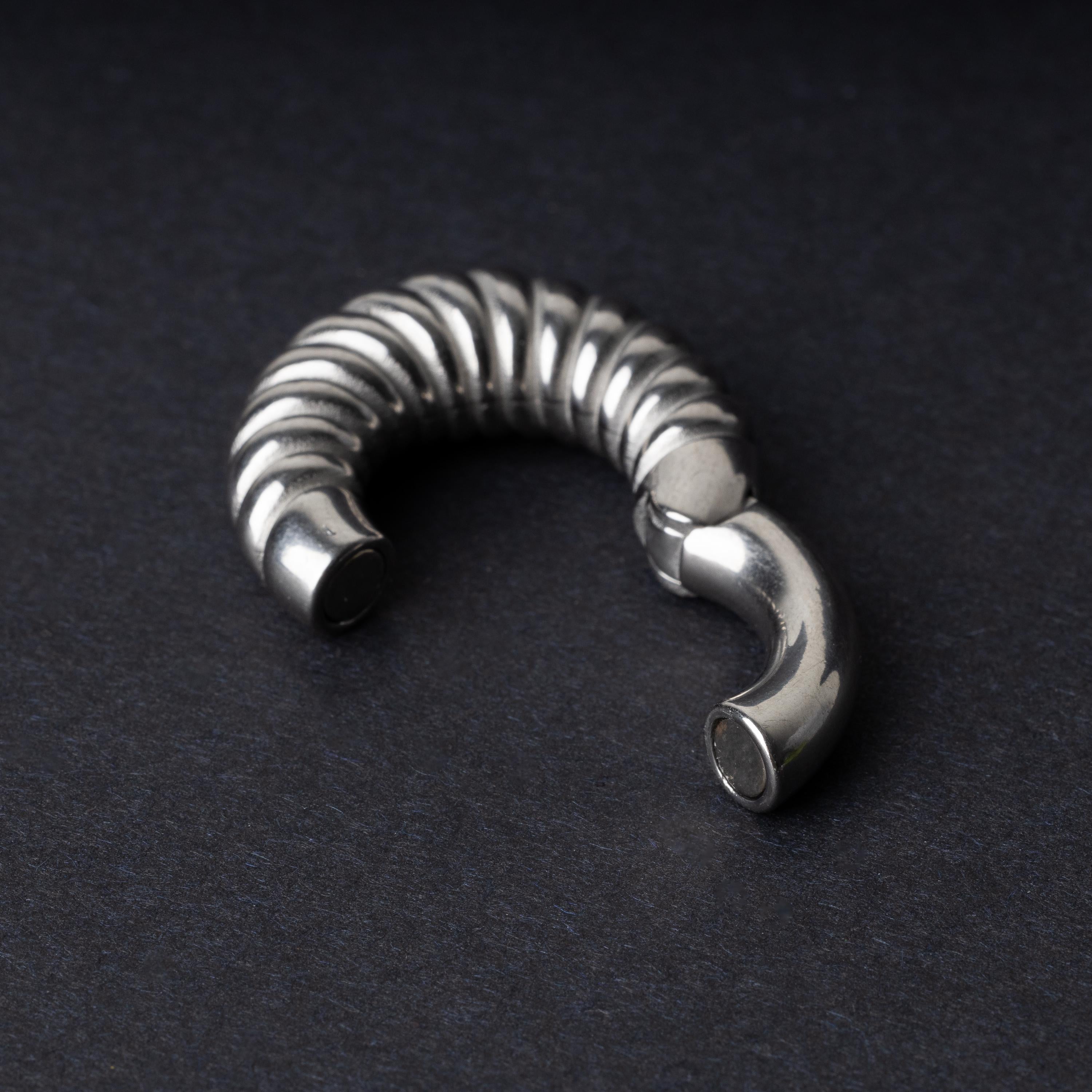 Silver textured hoop rings with a ridged design on a dark background.