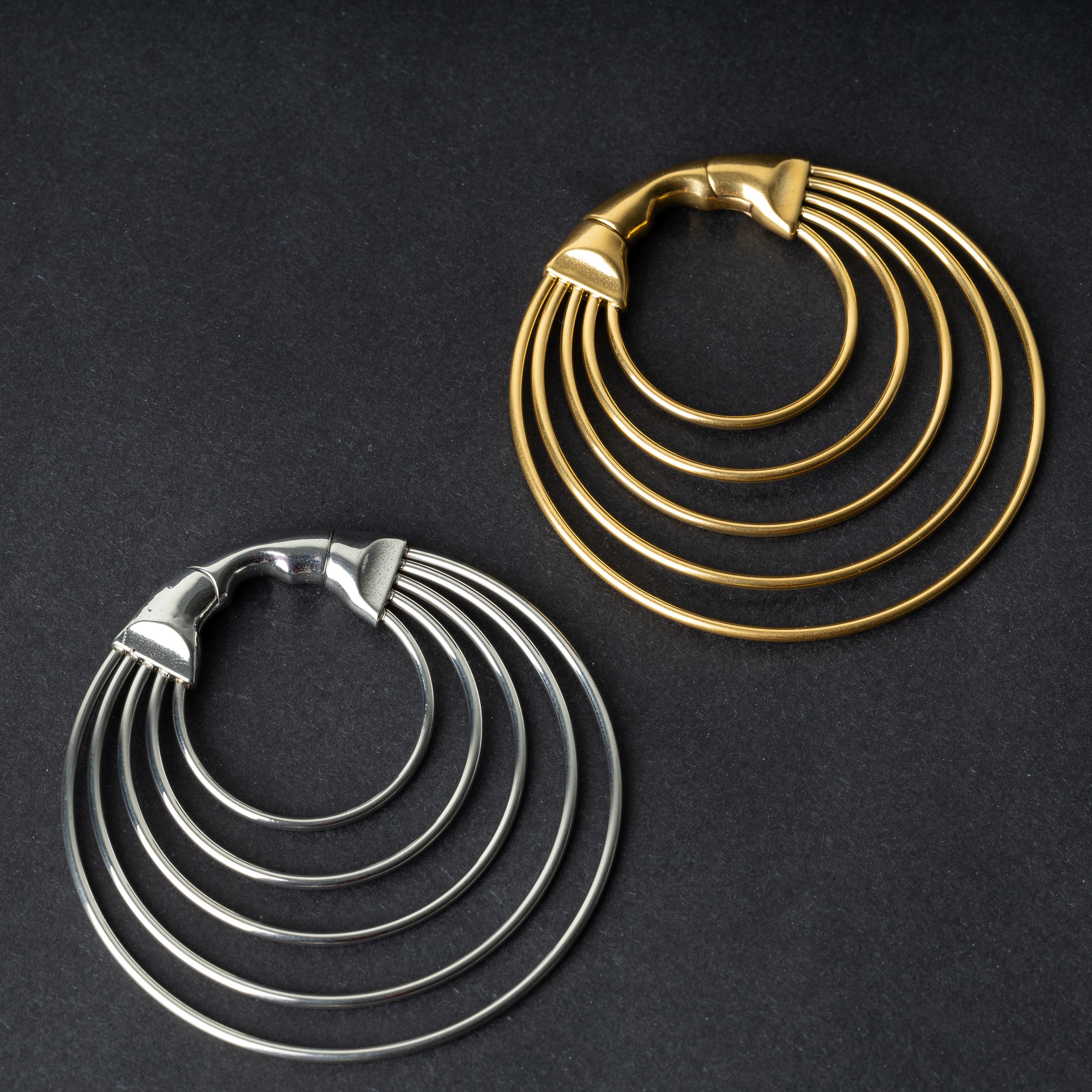  multi-hoop ear weights in polished gold and silver, featuring five cascading hoops and a seamless hinge closure, displayed on a dark background.

