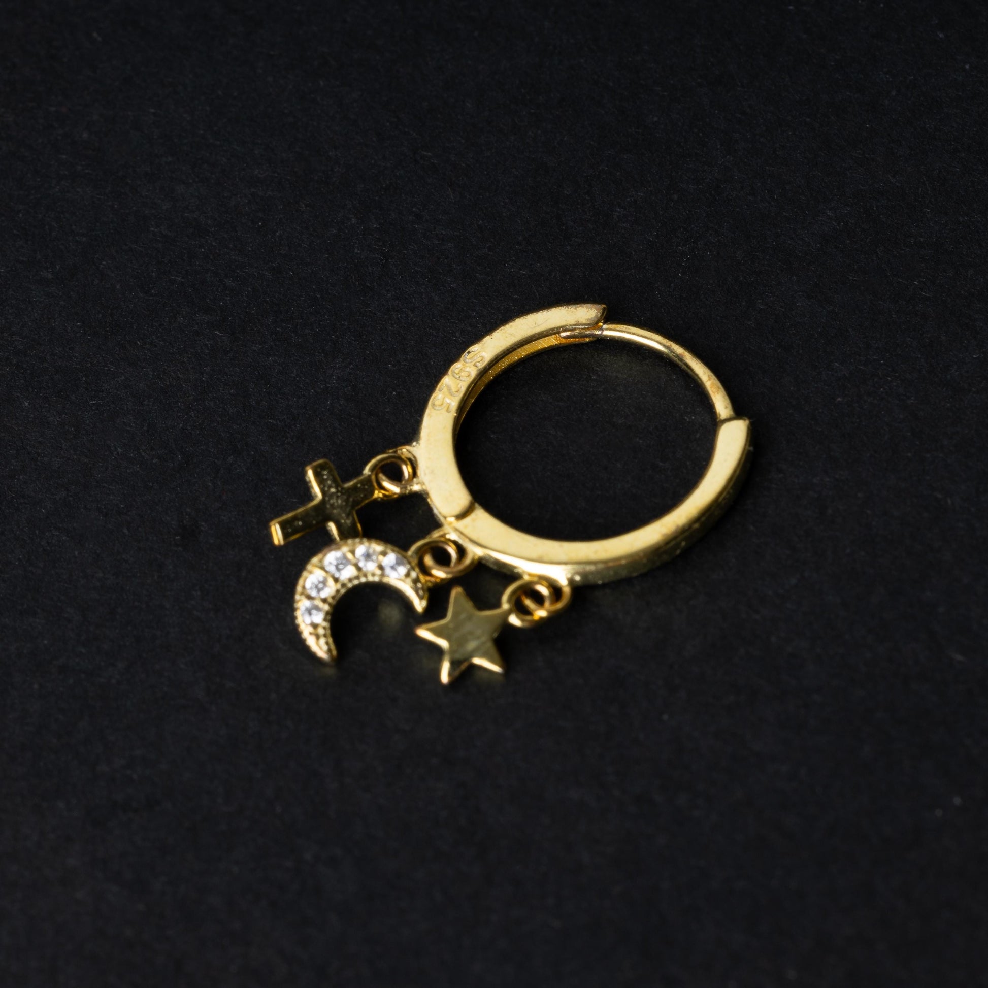 Gold clicker ring adorned with a moon charm encrusted with crystals, a star, and a cross, displayed on a dark background.