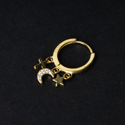 Gold clicker ring adorned with a moon charm encrusted with crystals, a star, and a cross, displayed on a dark background.