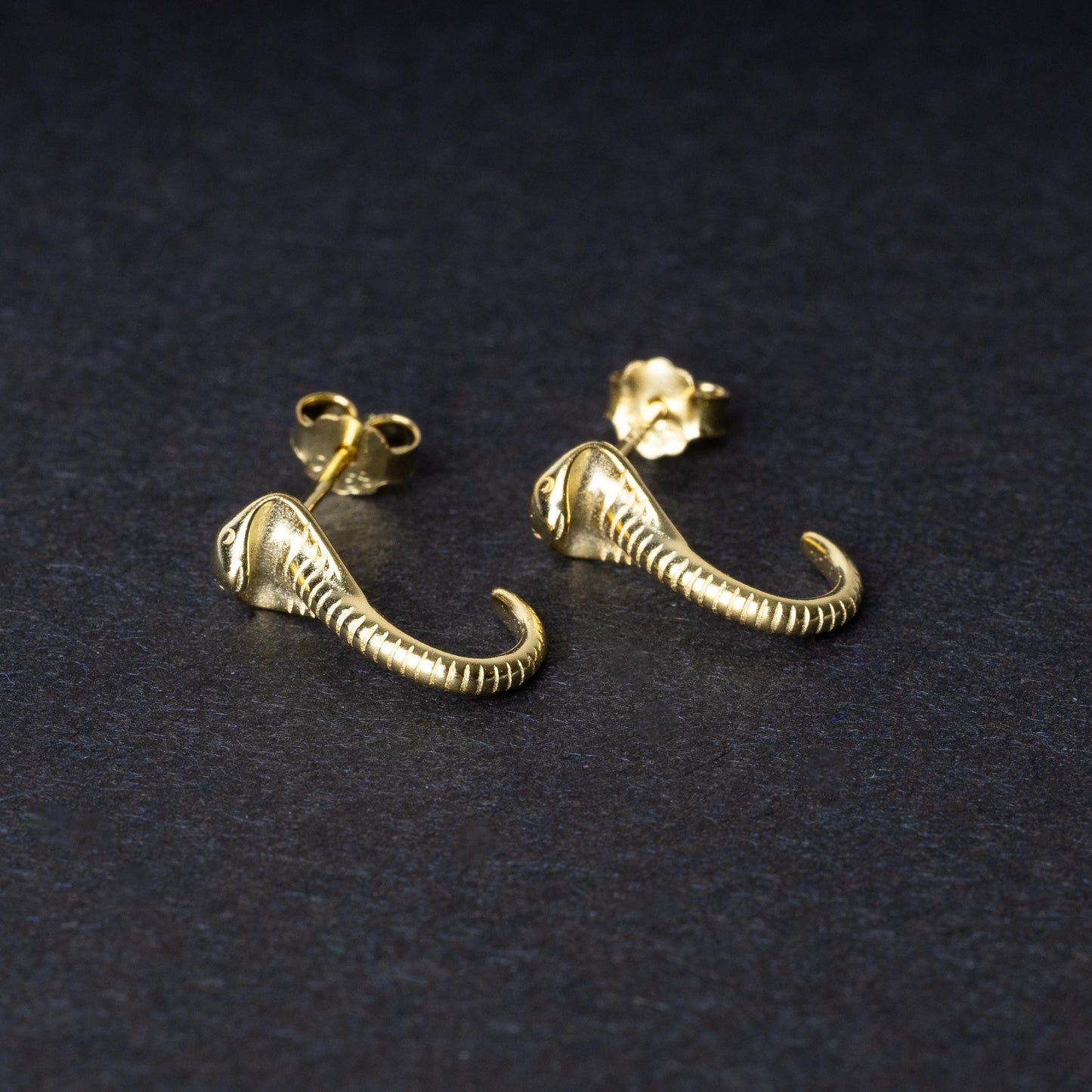 Gold-toned cobra-shaped stud earrings with intricate detailing, crafted from 925 sterling silver, displayed on a black background.