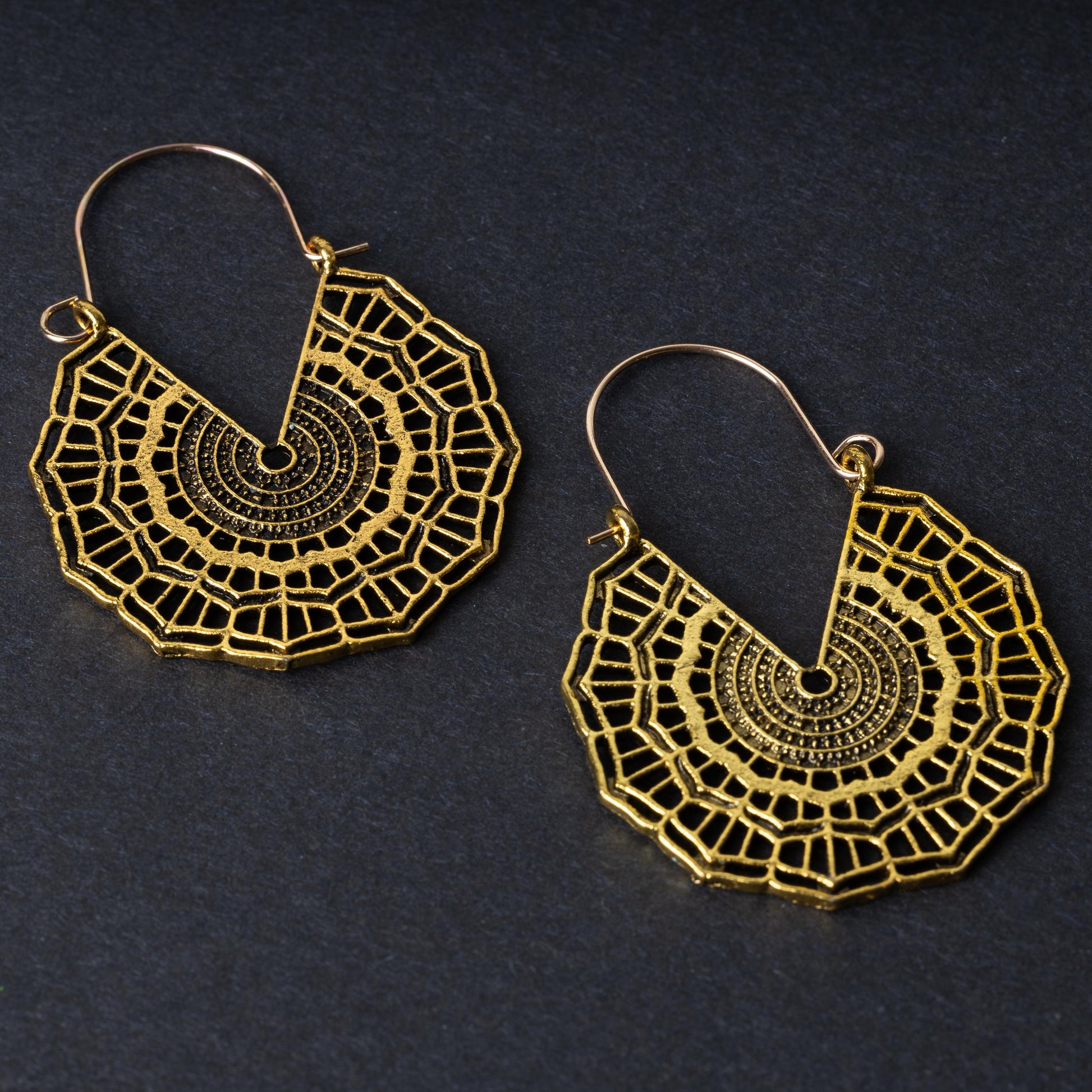 Mandala-inspired earrings in gold with intricate geometric designs, displayed on a dark background.