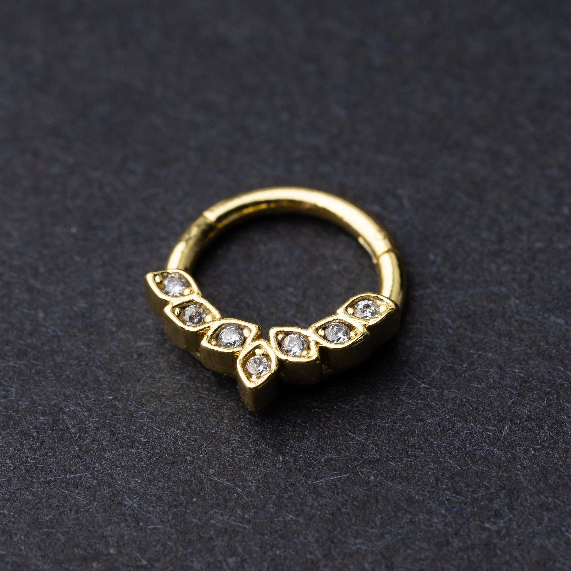 Marquise gemstone stainless steel clicker in gold displayed on a dark textured background.